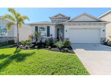 Charming single-Gathering home featuring lush green grass, beautiful landscaping, and a two-car garage at 5277 Grove Mill Loop, Bradenton, FL 34211