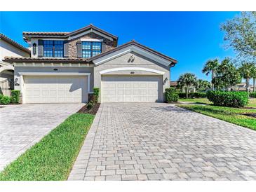 Charming townhome featuring a two-car garage, stone accents, and well-manicured landscaping at 5931 Wake Forest Run # 104, Bradenton, FL 34211