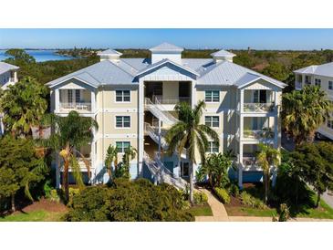 Three-story condo building with balconies, painted in soft yellows and blues, surrounded by palm trees and lush greenery at 7730 34Th W Ave # 103, Bradenton, FL 34209