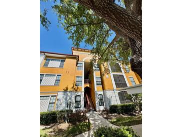 Inviting mustard colored condo building with mature trees and tidy landscaping on a bright, sunny day at 8351 38Th Street E Cir # 302, Sarasota, FL 34243