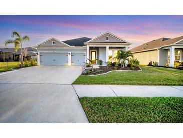 Charming single-story home with a manicured lawn, colorful sunset, and a two-car garage at 11021 Moonsail Dr, Parrish, FL 34219