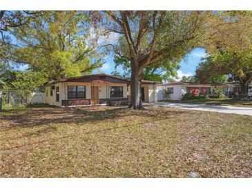Quaint single-story home featuring a covered entrance, complemented by mature trees in a well-maintained yard at 124 E 119Th Ave, Tampa, FL 33612
