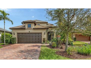 Charming home exterior with a well-maintained lawn, brick driveway, mature tree, and two-car garage in a tranquil setting at 17440 Hampton Falls Ter, Bradenton, FL 34202