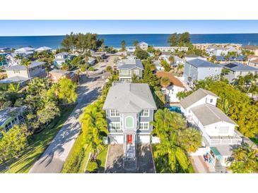 Beautiful aerial view of a two-story home near the ocean with lush green landscaping and a grey roof at 2300 Avenue B, Bradenton Beach, FL 34217