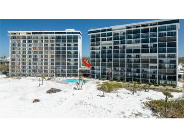 Beachfront condos featuring a swimming pool surrounded by palm trees and well-maintained landscaping at 20 Whispering Sands Dr # 301, Sarasota, FL 34242