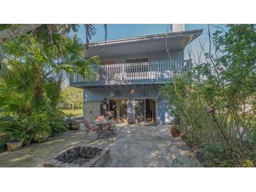 A cozy backyard patio with a fire pit and outdoor seating, surrounded by lush tropical landscaping and a two story home at 2230 Myakka Rd, Sarasota, FL 34240