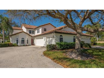 Beautiful two-story home with a red tile roof, a three-car garage and a large shady tree in the front yard at 4404 Calle Serena, Sarasota, FL 34238