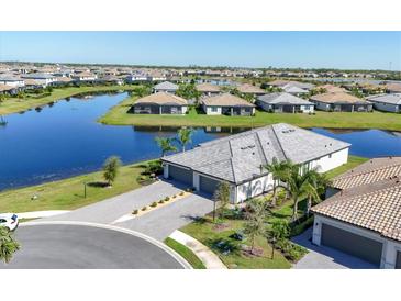 Beautiful aerial view of a modern home surrounded by a lake, landscaped yard, and a gray tile roof at 5311 White Sand Cv, Bradenton, FL 34211