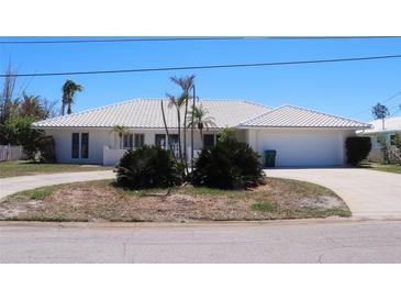 Single story home featuring a white tiled roof, circular driveway, and tidy landscaping at 618 Gladstone Ln, Holmes Beach, FL 34217