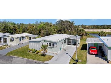 Well-maintained home with green siding, driveway, manicured lawn, and mature landscaping in a tranquil neighborhood setting at 633 Cervina S Dr, Venice, FL 34285