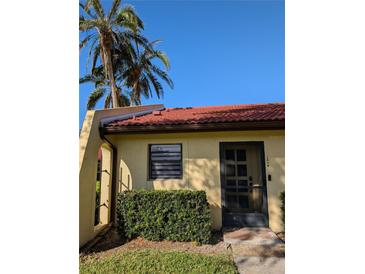 Charming home featuring a red tile roof, verdant shrubbery and beautiful palm trees against a clear blue sky at 1216 58Th W St, Bradenton, FL 34209