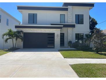 Modern two-story home boasts a dark garage door, manicured lawn, and stone accents for curb appeal at 3204 W Grace St, Tampa, FL 33607