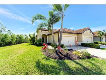 Charming home with a tile roof, manicured lawn, and beautiful landscaping with palm trees and red bromeliads at 324 Casalino Dr, Nokomis, FL 34275