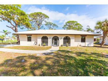 Charming single-story home featuring arched windows, a walkway, mature trees, and well-maintained landscaping at 411 S Oxford Dr # 411, Nokomis, FL 34275
