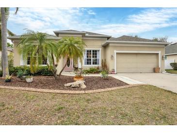 Charming home with a manicured lawn and mature landscaping, including decorative stone and lovely palm trees at 5806 43Rd E Ct, Bradenton, FL 34203