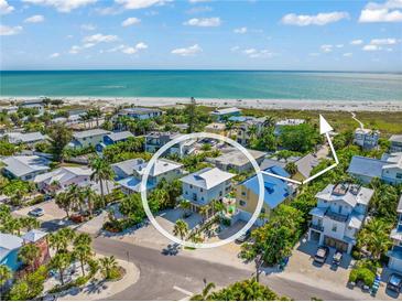 Stunning aerial view of a coastal home near a pristine beach and turquoise waters, surrounded by lush tropical greenery at 785 Jacaranda Rd, Anna Maria, FL 34216
