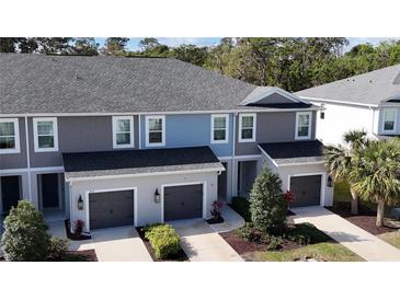 A charming townhome features a gray roof, gray and blue siding, and well-manicured landscaping at 8521 Canyon Creek Trl, Parrish, FL 34219
