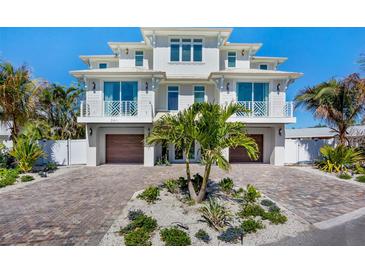 Stunning waterfront home boasting a private brick driveway, mature palms, and dual wooden garage doors at 244 Willow Ave, Anna Maria, FL 34216