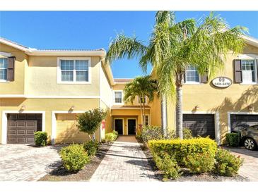 Inviting townhome exterior with well-manicured landscaping, attached garages, and a charming brick walkway to the front doors at 5450 Soapstone Pl # 9-103, Sarasota, FL 34233