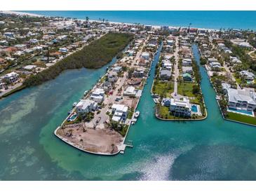Stunning aerial view of waterfront homes with private docks and boats on a sunny day near a sandy beach at 619 Bayview Dr, Longboat Key, FL 34228