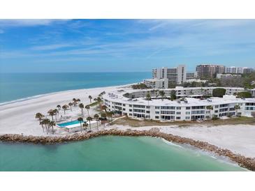 Stunning aerial view of beachfront condos, showcasing the pool, white sands, and turquoise waters at 100 Sands Point Rd # 225, Longboat Key, FL 34228