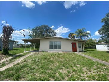 Exterior of a home with neutral paint, carport, small yard, and a bright red front door at 21114 Gladis Ave, Port Charlotte, FL 33952