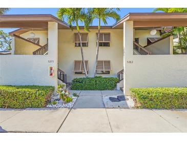 Two-story condo exterior featuring shuttered windows, lush landscaping, and a well-maintained walkway at 5275 Willow Links # 50, Sarasota, FL 34235