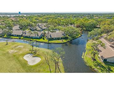 Stunning aerial view of golf course home with waterfront views, surrounded by lush landscaping and mature trees at 5688 Pipers Waite # 50, Sarasota, FL 34235