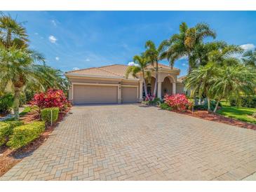 Beautiful home featuring a three-car garage, tile roof, brick paver driveway, and lush tropical landscaping at 8004 River Preserve Dr, Bradenton, FL 34212