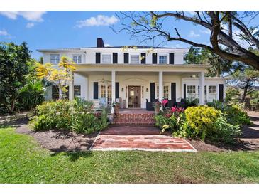 Charming home featuring a brick pathway, lush landscaping, and a welcoming front porch with columns at 813 Hudson Ave, Sarasota, FL 34236