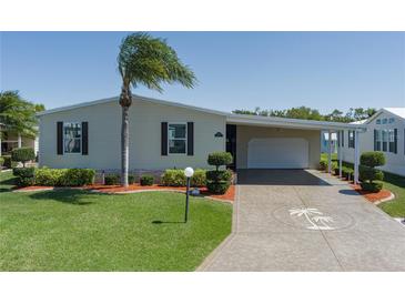 Charming single-story home featuring a carport, well-maintained lawn, and decorative palm tree driveway inlay at 8424 Regal Way, Palmetto, FL 34221