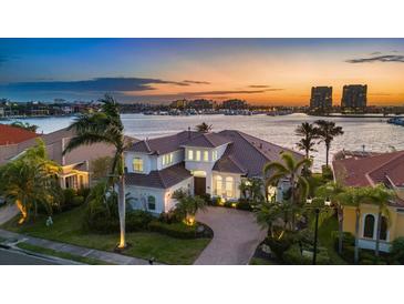 Waterfront home featuring lush landscaping, a tile roof, and a circular driveway overlooking a scenic harbor view at sunset at 125 12Th E Ave, Palmetto, FL 34221