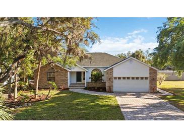 Charming single-story home featuring a brick and siding facade, a well-manicured lawn, and a two-car garage at 4444 Robin Hood Trl W, Sarasota, FL 34232
