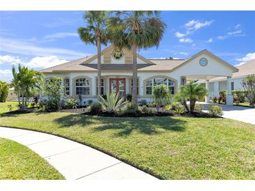 Inviting home with manicured lawn, lush landscaping, palm trees and attached portico at 4624 Blue Marlin Dr, Bradenton, FL 34208