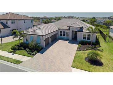 Stunning single Gathering home with a paver driveway, tile roof, 2 car garage, and manicured lawn at 6172 Lungo Lago Dr, Sarasota, FL 34241
