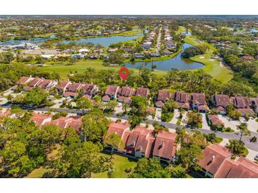 An aerial view showcasing the community's red tile roofs, golf course, and serene lake at 7713 Fairway Woods Dr # 902, Sarasota, FL 34238