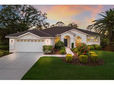 Beautiful home exterior showcasing a manicured lawn, arched windows, and tiled roof at sunset at 9408 Glen Abbey Ln, Sarasota, FL 34238