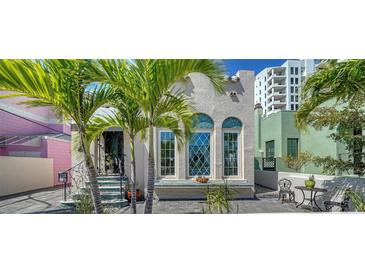 Charming home featuring arched windows and a quaint patio, framed by lush palm trees for a tropical feel at 446 Burns Ct, Sarasota, FL 34236