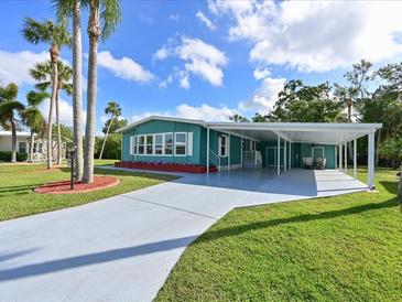 Charming home featuring a covered carport, well-manicured lawn, and vibrant landscaping at 5910 Majestic Way, Palmetto, FL 34221