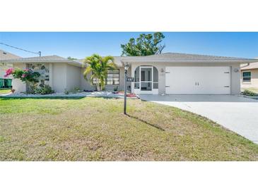 Charming single-story home featuring a manicured lawn, well-maintained landscaping, and an attached two-car garage at 6387 Shalimar St, Port Charlotte, FL 33981