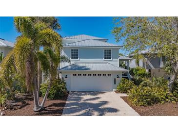 Charming two-story home with a two car garage, metal roof, and lush tropical landscaping at 4922 Commonwealth Dr, Sarasota, FL 34242