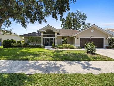 Beautiful single-story home with mature landscaping, manicured lawn, and a two-car garage at 555 Park Estates Sq, Venice, FL 34293
