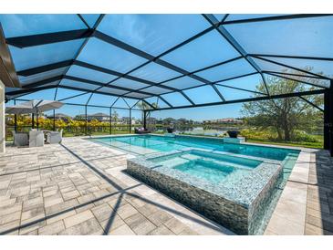 Stunning screened pool area with spa and outdoor dining, perfect for relaxing and entertaining with picturesque water views at 9487 Tequila Sunrise Dr, Sarasota, FL 34241