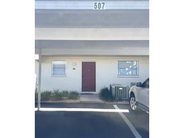 Exterior of condo featuring covered parking, a red door, and minimal landscaping at 507 Parkdale Mews # 507, Venice, FL 34285