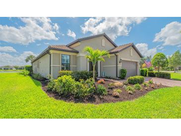 Beautifully landscaped front yard with a well-maintained lawn, palm tree, and colorful flowerbeds at 5562 Rain Lily Ct, Sarasota, FL 34238