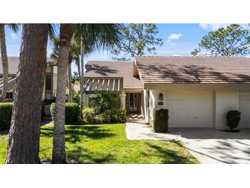 Charming home exterior with a manicured lawn, palm trees, and a walkway leading to the entrance at 3215 Sandleheath # 44, Sarasota, FL 34235