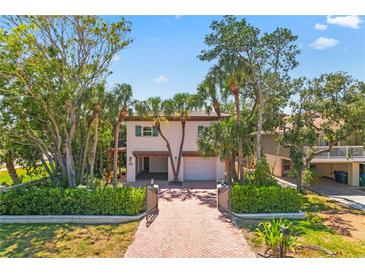 Charming two-story home with tropical landscaping and a brick-paved driveway leading to a two-car garage at 4002 6Th Ave, Holmes Beach, FL 34217