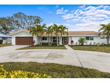 Charming single-story home with a beautiful tiled roof, well-manicured landscaping, and a spacious driveway at 611 Dundee Ln, Holmes Beach, FL 34217