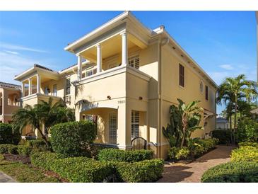 Elegant two-story home featuring a decorative balcony, lush landscaping, and a well-manicured walkway at 7665 Bergamo Ave, Sarasota, FL 34238