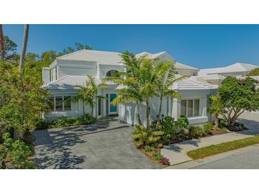 Beautiful two-story home with white tile roof, lush landscaping and paver driveway at 7782 Club Ln, Sarasota, FL 34238